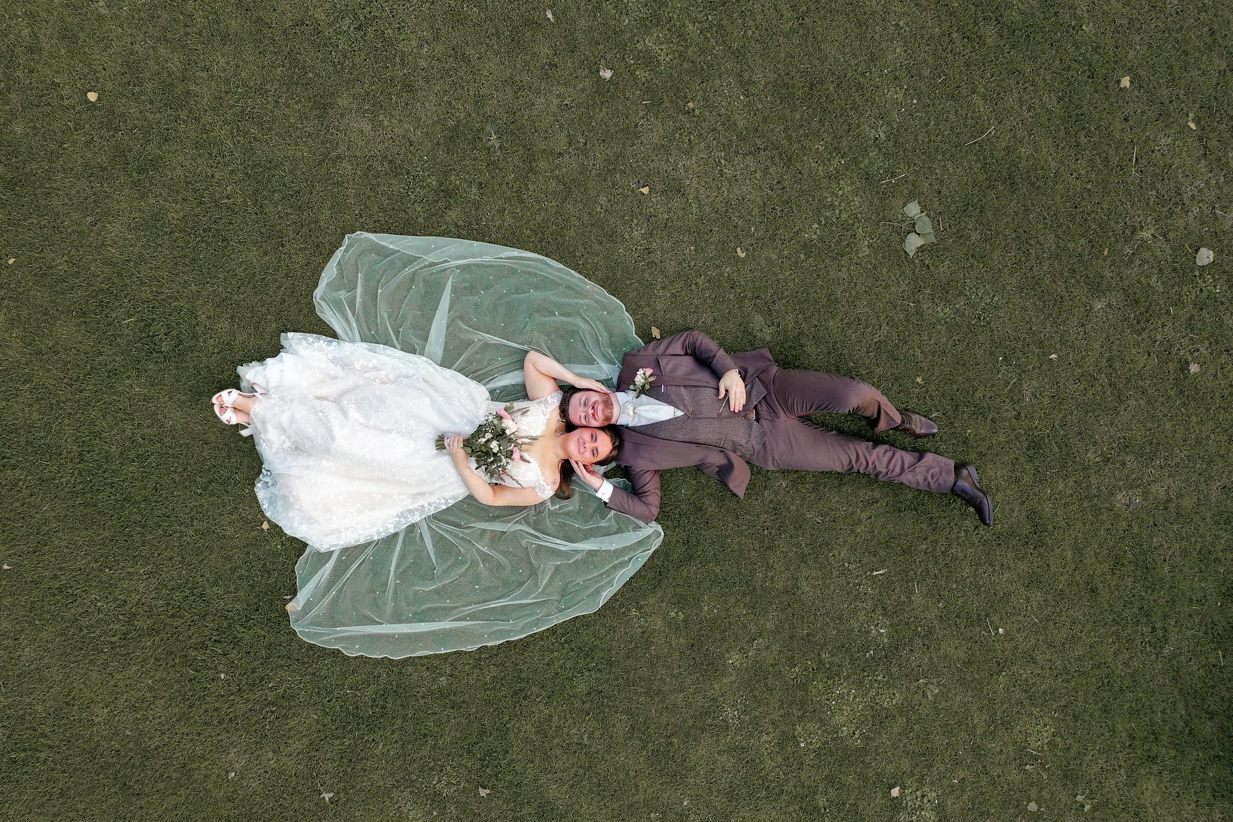 Les mariés allongés dans l'herbe, vue à la verticale du drone